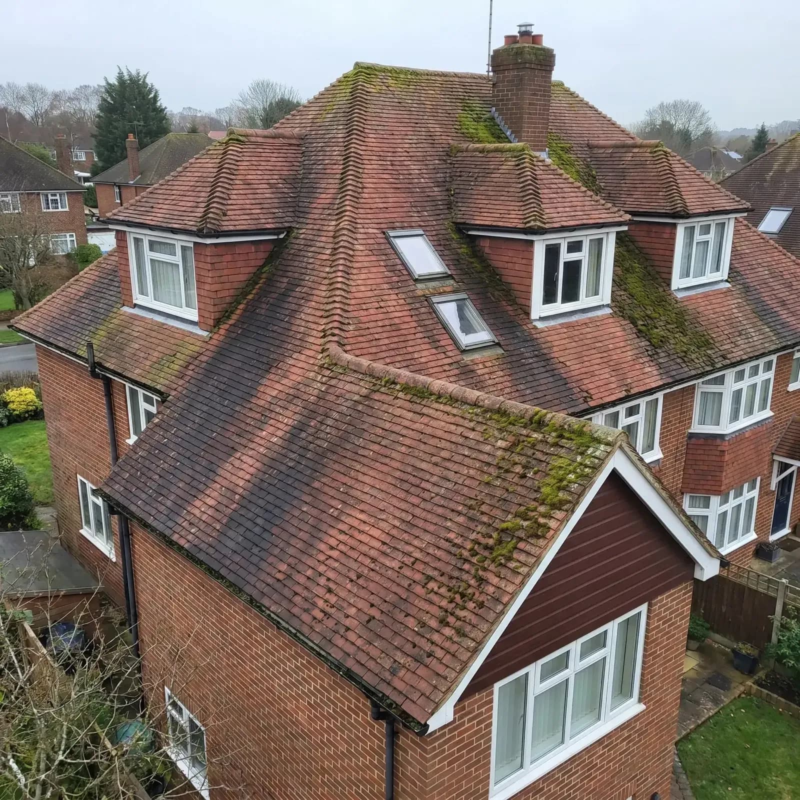 Clay tile roof with dormers covered in moss, seen from above